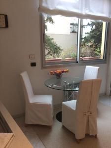 une salle à manger avec une table en verre et des chaises blanches dans l'établissement Appartamento "Renata" in residence Cap Roux Eze Borde de Mer Costa Azzurra, à Èze