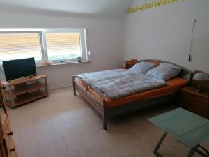 Schlafzimmer mit einem Bett, einem Schreibtisch und einem TV in der Unterkunft Zur goldenen Glocke Inhaberin Katja Koppik in Dassel