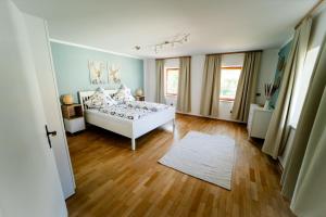 a bedroom with a white bed and a wooden floor at Ferienhaus Drasch in Lalling