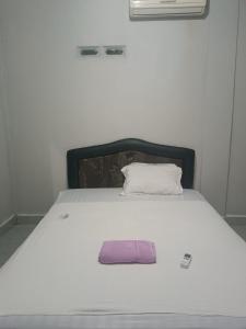 a white bed with a purple pillow on it at Pika Homestay in Plambi