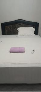 a white bed with a pink pillow on it at Pika Homestay in Plambi