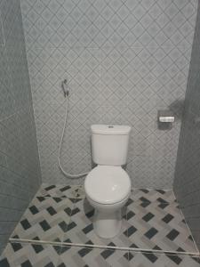 a bathroom with a white toilet in a tiled room at Pika Homestay in Plambi