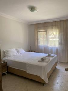 a bedroom with a large bed with white sheets and a window at Side’de havuzlu daire in Side