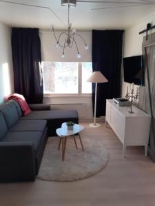 a living room with a black couch and a table at Huone Seesteisessä Mummolassa in Kalajoki