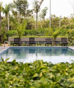 una piscina con bancos y palmeras en Between Beach and Historic Center in Fantastic Location! en Xcumpich