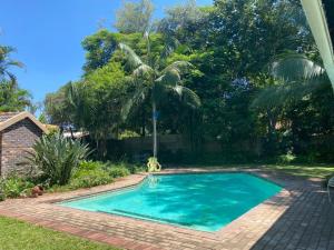 a swimming pool in a yard with a palm tree at Four Seasons Guesthouse - Hardekool 7 in Lephalale