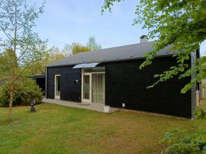a black house with a dog sitting in front of it at Silkeborg Legoland luxury cabin in Silkeborg