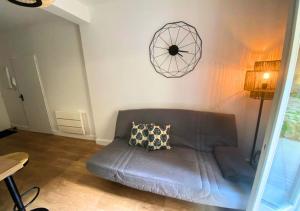 - un salon avec un canapé et un réveil sur le mur dans l'établissement Côté Cour - Poitiers - La Conciergerie., à Poitiers