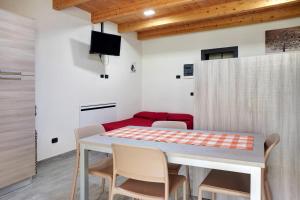 uma sala de jantar com uma mesa e cadeiras e um sofá vermelho em Agriturismo L'isola del Cavallo 2 em Desco