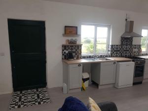 a kitchen with white cabinets and a green door at Lavender lane cottage in Tralee