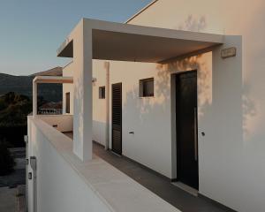 a white house with a door and a balcony at Dawn & Dusk - Modern Two Bedroom Apartment with Mountain Views in Čilipi