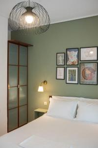 a bedroom with a white bed and a green wall at OTIUM living in Volos