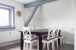 a dining room with a black table and white chairs at Schöne Ferienwohnung für 4-6 Personen erwartet Sie im Oberharz in Sankt Andreasberg