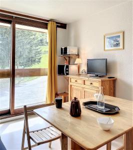 ein Wohnzimmer mit einem Holztisch und einem TV in der Unterkunft travelski home classic - Résidence Soyouz in Le Corbier