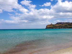 uma praia com água azul e uma montanha ao fundo em Ethos Rooms em Cagliari