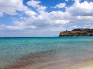 a beach with blue water and a mountain in the background at Ethos Rooms in Cagliari