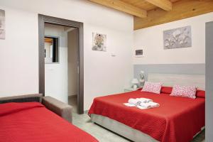 - une chambre avec 2 lits dotés de draps rouges et de plafonds en bois dans l'établissement Agriturismo L'isola del Cavallo 4, à Desco