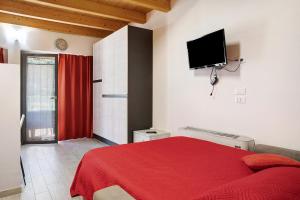 a bedroom with a red bed and a flat screen tv at Agriturismo L'isola del Cavallo 4 in Desco
