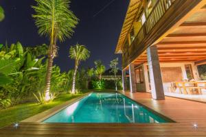 a swimming pool in front of a house with palm trees at Melali Bingin in Uluwatu