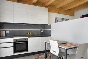 une cuisine avec des placards blancs et une table avec des chaises dans l'établissement Agriturismo L'isola del Cavallo 3, à Desco