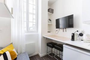 biała kuchnia z biurkiem i telewizorem na ścianie w obiekcie Lavie Maison Bordeaux Bliss Studio w mieście Bordeaux