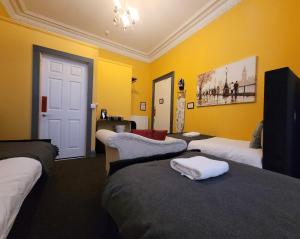 a hotel room with three beds and yellow walls at Stay - NO59 in Edinburgh