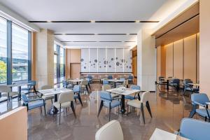 a dining room with tables and chairs and windows at Fairfield by Marriott Beijing Daxing Airport in Beijing