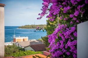 een uitzicht op het water en de paarse bloemen bij Luna Tsuki Two in Rovinj