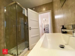 La salle de bains est pourvue d'une douche et d'un lavabo blanc. dans l'établissement Casas da Biquinha, à Sintra