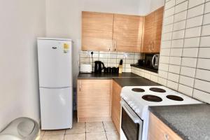 a kitchen with a white refrigerator and wooden cabinets at Come on in Lucas Street Newport Train Station Sleep upto 8 in Newport