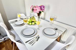 a white table with plates and a vase of fruit at Come on in Lucas Street Newport Train Station Sleep upto 8 in Newport