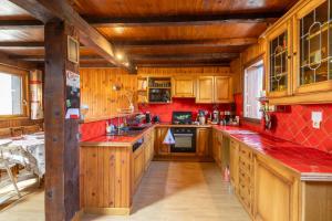a large kitchen with wooden cabinets and red tiles at La Perle des Pyrénées - Maison pour 8 in Formiguères +7 photos