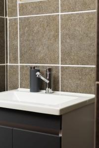 a white sink in a bathroom with a tiled wall at Honolulu Lifestyle Guest Lodge in Burgersfort