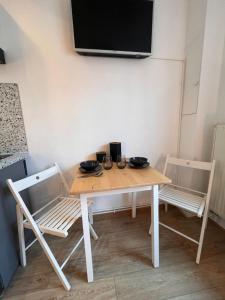 stół z 2 krzesłami i telewizor na ścianie w obiekcie Studio « Le petit Prat » w mieście Colomiers