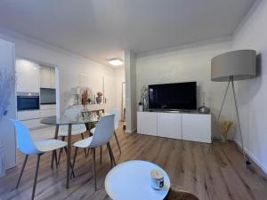 uma sala de estar com uma mesa e cadeiras e uma televisão em Stylish 1-bedroom condo close to exhibition square em Basileia