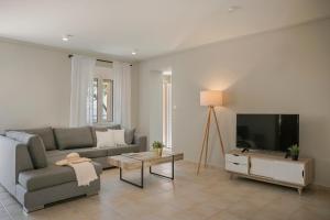 a living room with a couch and a flat screen tv at Sandy & Sofia in Katelios