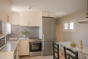 a kitchen with white cabinets and a stainless steel refrigerator at Sandy & Sofia in Katelios