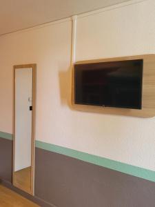 telewizor z płaskim ekranem wiszący na ścianie w obiekcie Premiere Classe Lyon Nord Dardilly w mieście Dardilly