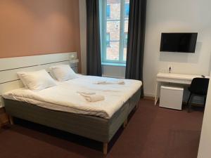 een slaapkamer met een bed, een bureau en een televisie bij Ahlgrens Hotell Bed & Breakfast in Gävle