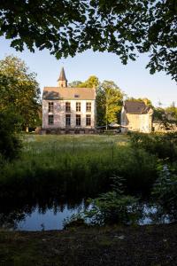 une ancienne maison en pierre avec une réflexion dans un étang dans l'établissement Treehouse 'Morgenrood' Ryckevelde 1451, à Damme