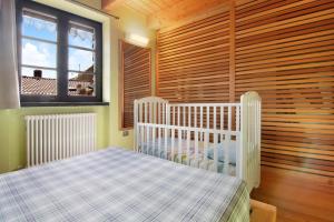 a white crib in a room with wooden walls at Casa Pollicina in Margno