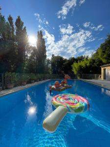 a swimming pool with two people on an inflatable at Mas des Amarens in Malaucène