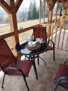 een tafel met een taart en twee stoelen op een veranda bij Apartmani Šarović Tara 2 in Rača