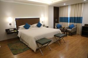 a hotel room with a large bed and two chairs at Four Points by Sheraton Vadodara in Vadodara