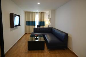 a living room with a black leather couch and a tv at Four Points by Sheraton Vadodara in Vadodara
