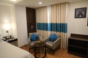 a hotel room with a bed and a chair and a table at Four Points by Sheraton Vadodara in Vadodara