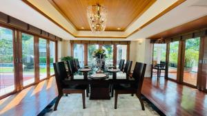 a dining room with a black table and chairs at Yizen Beachfront Seaview Villa in North Pattaya