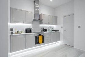 a kitchen with white cabinets and a yellow towel at LiveStay-Modern & Stylish Apartments in Didcot in Didcot