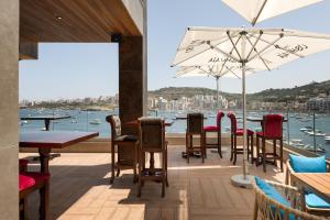 un restaurante con mesas y sillas y vistas al agua en Ushuaia Playa Xemxija Boutique Hotel, en St Paul's Bay