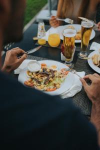 Pelican Alvor في ألفور: مجموعة من الناس يجلسون على طاولة مع طبق من الطعام